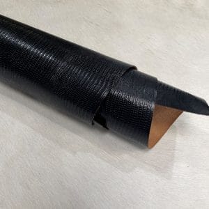 Lizard embossed cowhide black color rolled view. Lizard Embossed Cowhide is a vegetable-tanned leather with a bold, exotic texture. At 3 oz thick and medium temper, it’s ideal for bags, belts, wallets, and costume work. This high-quality cowhide is tanned in Mexico and embossed with a sharp, consistent lizard pattern.