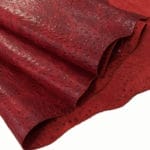 Red Alba | Avetco Leather Hides and Eva Foam Ostrich Embossed Cow Leather is made of European leather with a unique embossed grain texture that resembles Ostrich skin. Its rough appearance, complete with grooves and bumps, makes it beautiful and durable. The leather has a waxed finish that adds smoothness and shine to its surface. This collection uses chrome tanning, which gives it a luxurious and rich look.