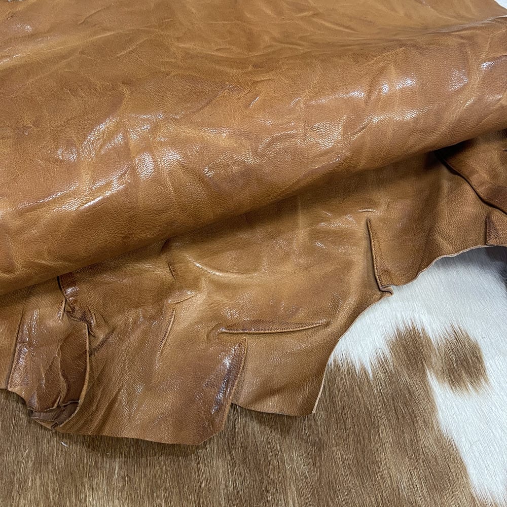 SL-209TAN Goat 1 The Goatskin-washed Leather Collection offers an exclusive range of leather that undergoes a special tanning process, resulting in a unique and irregular texture. The leather's shrunken grain creates a striking and dynamic appearance, while its distressed look adds to its appeal. The thickness of the leather adds to its durability and dependability. The collection features a variety of warm and distinct colors that make it ideal for creating timeless looks.