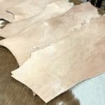 This is a 2LB full-grain tooling Cow leather made using a natural vegetable tanning process, which is perfect for small projects like jewelry making, altered art, wallets, portraits, clutches, holsters, knife sheaths, key fobs, and more. The leather is made from 100% cowhide and is tanned naturally, with a thickness ranging from 6 oz - 8 oz. The leather color is natural and will darken over time if left untreated or exposed to sunlight. It's important to note that the hide may have scratches, different tones, and various shades of natural leather color. It has a medium to stiff texture and comes in various sizes.
