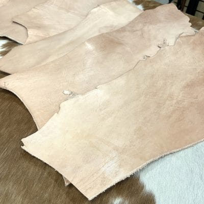 This is a 2LB full-grain tooling Cow leather made using a natural vegetable tanning process, which is perfect for small projects like jewelry making, altered art, wallets, portraits, clutches, holsters, knife sheaths, key fobs, and more. The leather is made from 100% cowhide and is tanned naturally, with a thickness ranging from 6 oz - 8 oz. The leather color is natural and will darken over time if left untreated or exposed to sunlight. It's important to note that the hide may have scratches, different tones, and various shades of natural leather color. It has a medium to stiff texture and comes in various sizes.