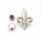Nickel Fleur De Lis decorative rivet set with matching flat round cap and snap components arranged neatly on a clean white background.