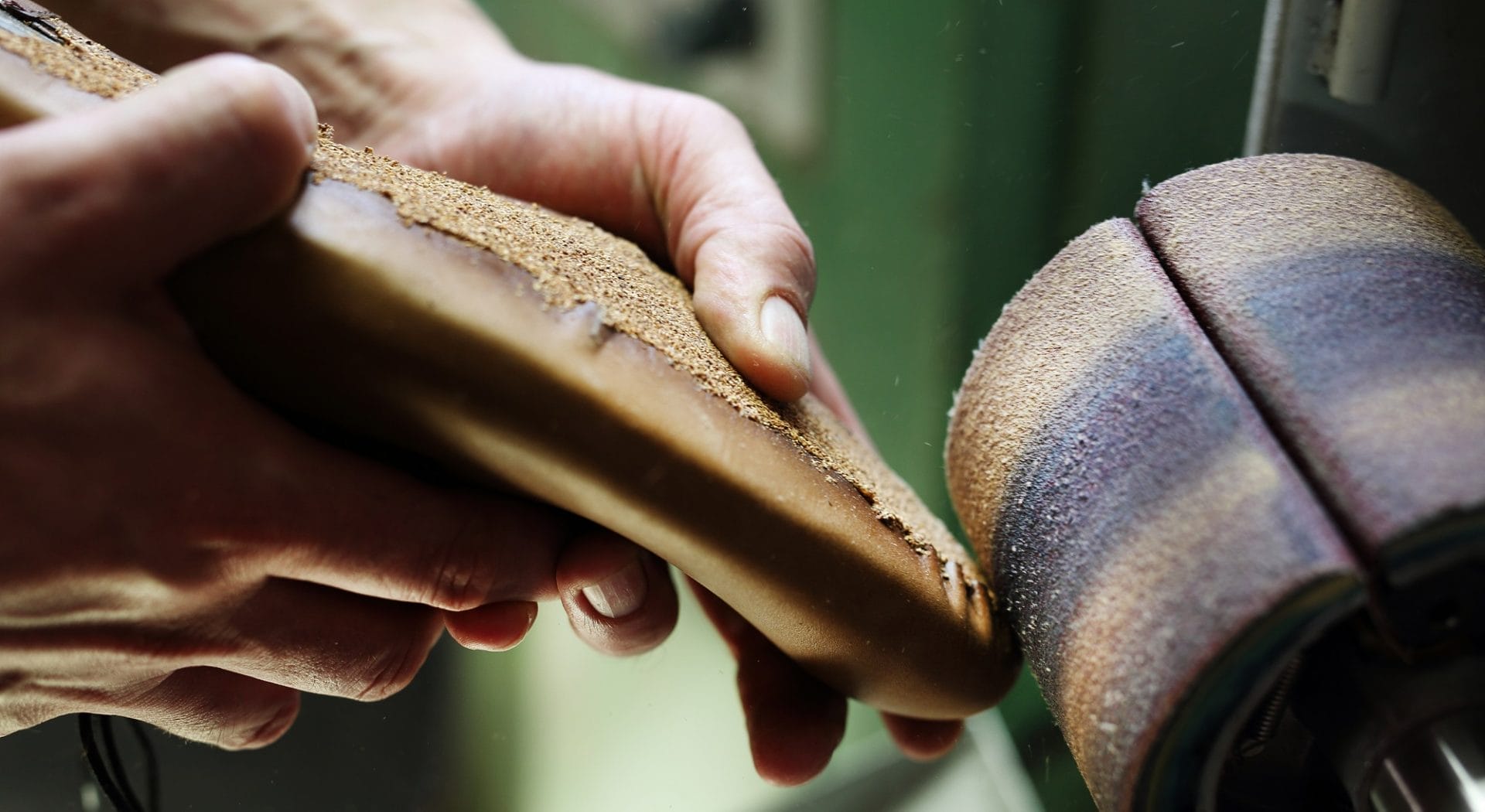 "Craftsman sanding leather shoe sole showcasing traditional shoemaking."