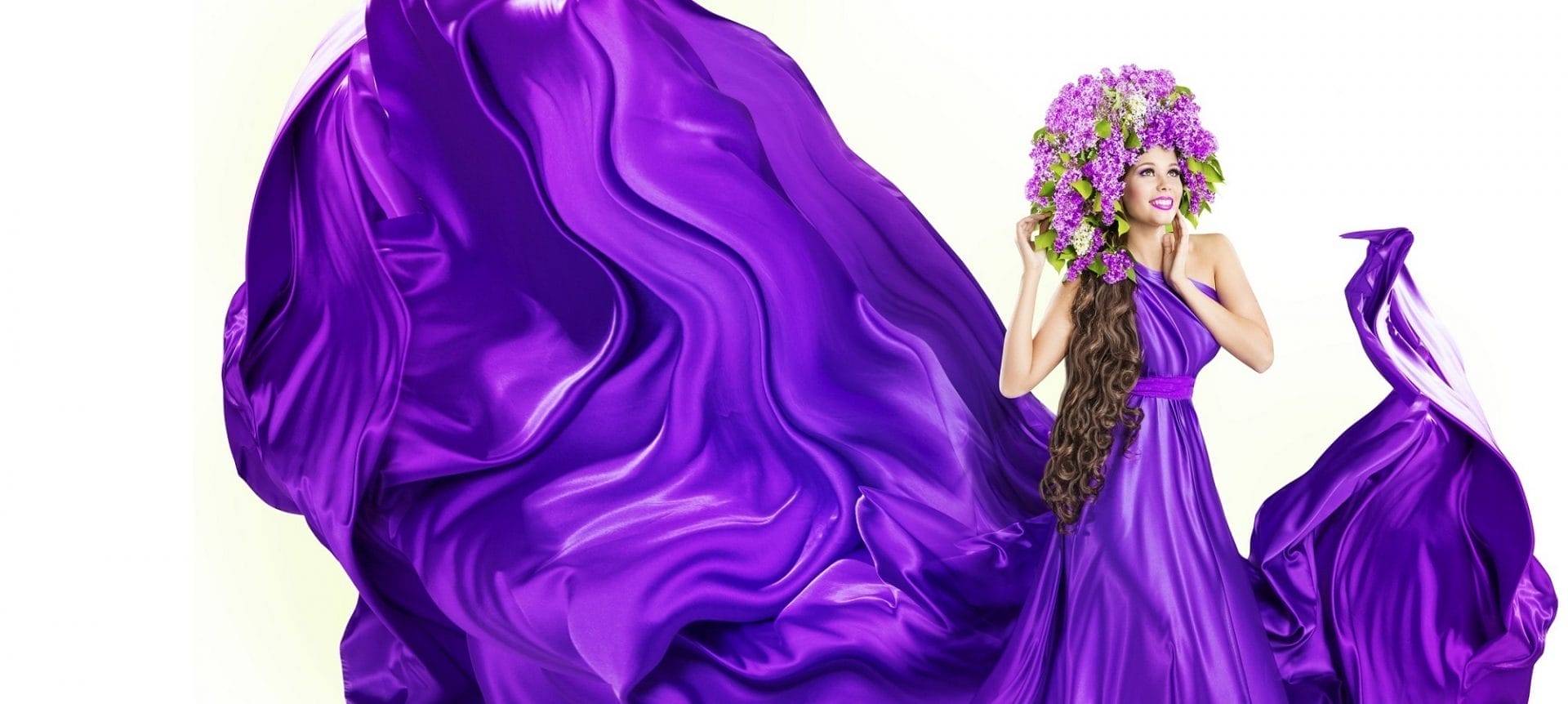 Fashion model in flowing purple gown accessorized with floral headdress