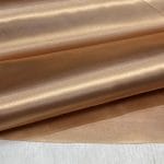 Bonded polyester satin with tricot backing, 58" wide, 0.3 mm thick. Available in Black, Champagne, Rose, Beige Copper, Bronze Red & Silver.
