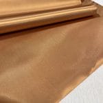 Bonded polyester satin with tricot backing, 58" wide, 0.3 mm thick. Available in Black, Champagne, Rose, Beige Copper, Bronze Red & Silver.