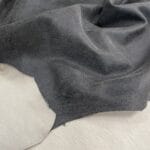 Black crackle leather with subtle pebble texture and off-white base, shown flat to highlight topcoat finish.