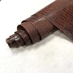 Rolled embossed cowhide leather in rustic brown with crocodile texture on a light background