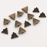 10mm Triangle Nailheads-Antique Brass-Avetco | Avetco Leather Hides and Eva Foam Close-up of 10mm triangle nailheads in antique brass finish with one prong on each side, displayed on a white background – Avetco.