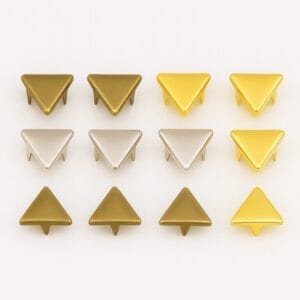 Three rows of 10mm triangle nailheads in Antique Brass, Nickel, and 14K Gold finishes, neatly arranged for color comparison – Avetco.