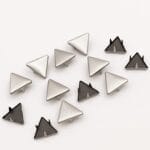 Detailed view of 10mm triangle nailheads in Nickel finish with black prongs, arranged in a scattered layout on white background – Avetco.