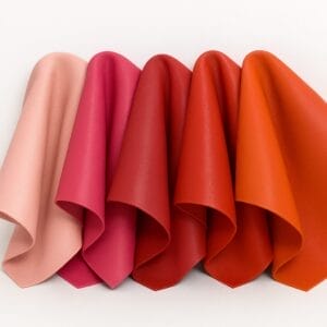 Lamb leather swatches in a spectrum of reds, oranges, and pinks on a white background.-Avetco