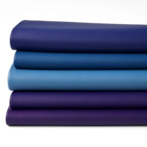 Stacked folded hides of smooth full-grain cow leather in blue and purple tones on a white background, part of the Milano Collection by Avetco