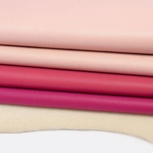Four stacked rolls of Milano cowhide leather in soft pink tones, featuring smooth-grain finish on a white fur background.-Avetco