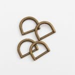 Four antique brass AVETCO D-rings arranged on a white background.