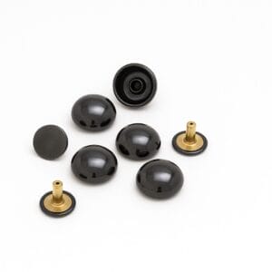 Shiny gunmetal dome rivets displayed on a white background, highlighting smooth dark gray reflective surfaces with brass posts.