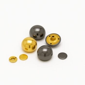 Gold and gunmetal dome rivets displayed side by side on a white background, showcasing color variation and reflective metallic finishes.